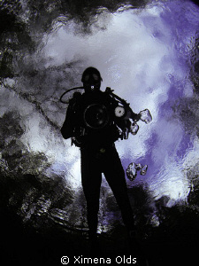 A diver entering a fresh water spring. Photo taken from t... by Ximena Olds 